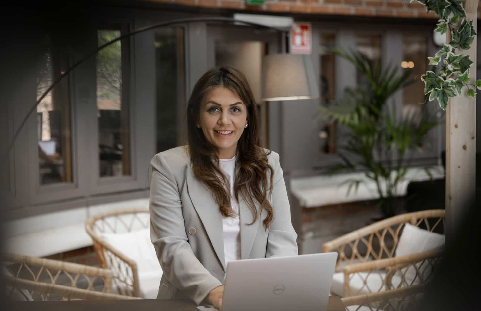 Kvinna i grå kavaj arbetar vid en laptop, representerar effektiv hantering av ekonomifunktion