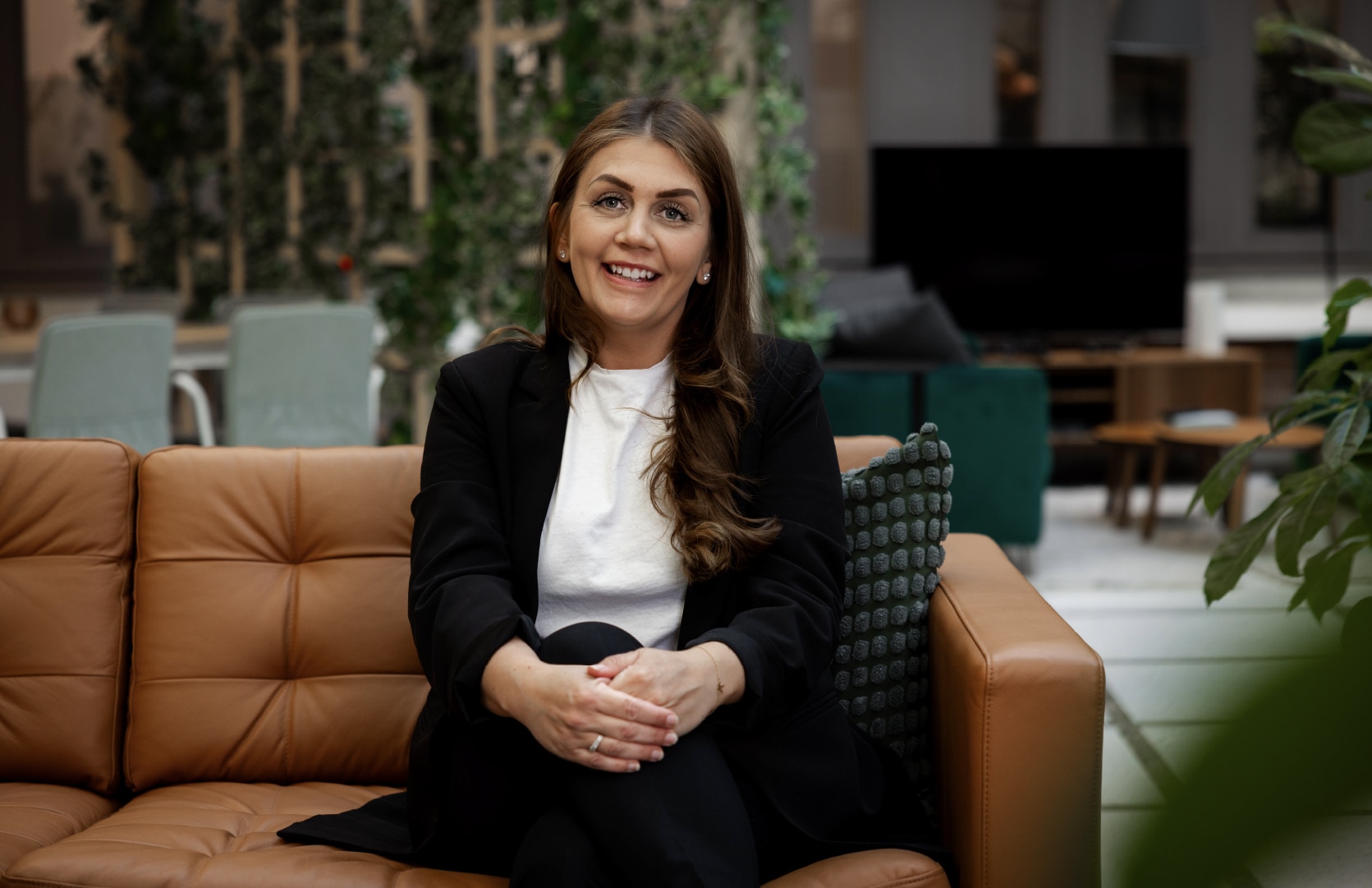 Kvinna sitter leende i en modern kontorsmiljö, redo att diskutera ekonomifunktion